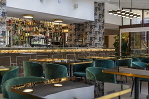 A modern bar area with a coffee machine, shelves of bottles, and green upholstered chairs. - Palazzo della Scala Spa Hotel Suites & Apartments (Lazise)
