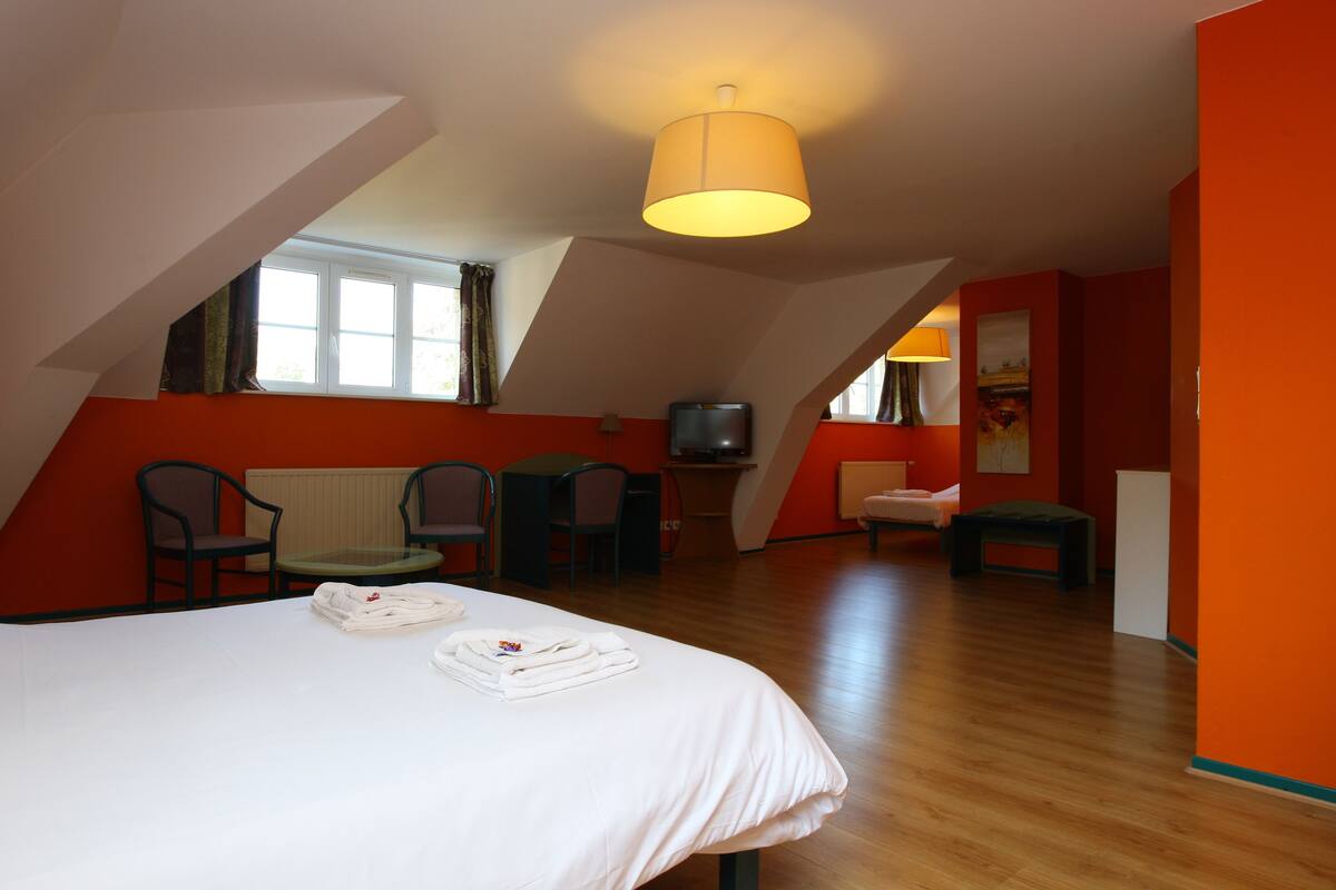 A hotel room with a bed, a desk, a chair, a TV, and a window.