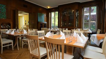 A dining area with wooden tables and chairs, set for a meal.