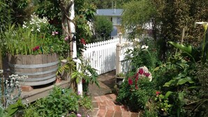 Un chemin de jardin menant à une clôture blanche, bordé de différentes plantes et fleurs.