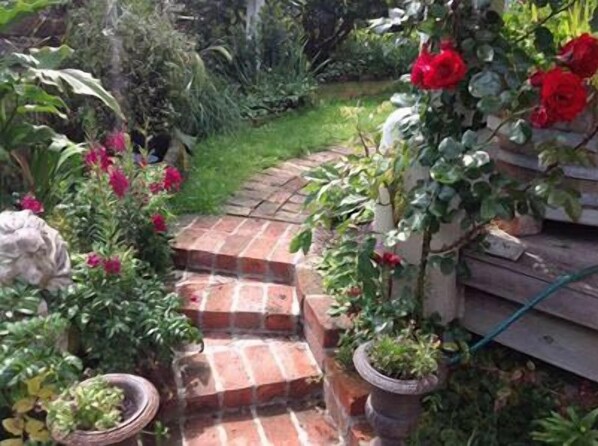 Un jardín con un camino de ladrillo que lleva a una terraza de madera.