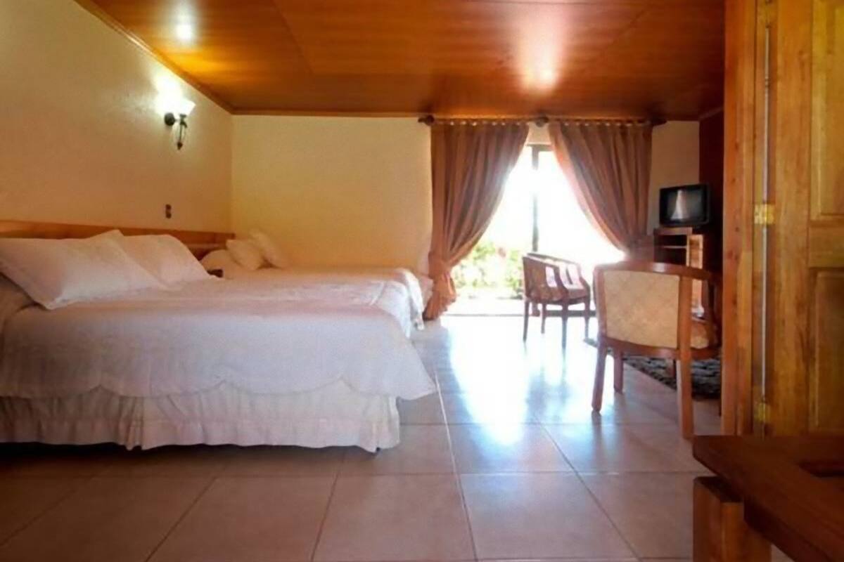 A bedroom with two beds, a TV, and a desk.