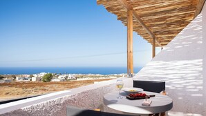 A terrace with a table set for two, overlooking a coastal landscape.