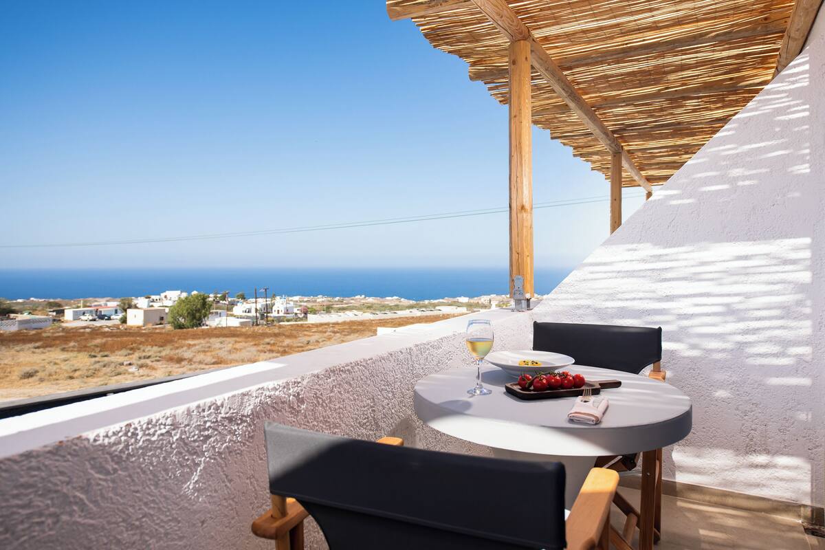 Terraço com mesa posta para dois, com vista para a paisagem costeira.