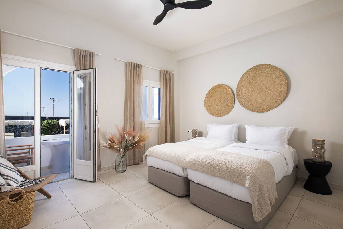 Quarto com cama, ventoinha no teto, mesa de cabeceira e vista para área externa por uma porta deslizante.