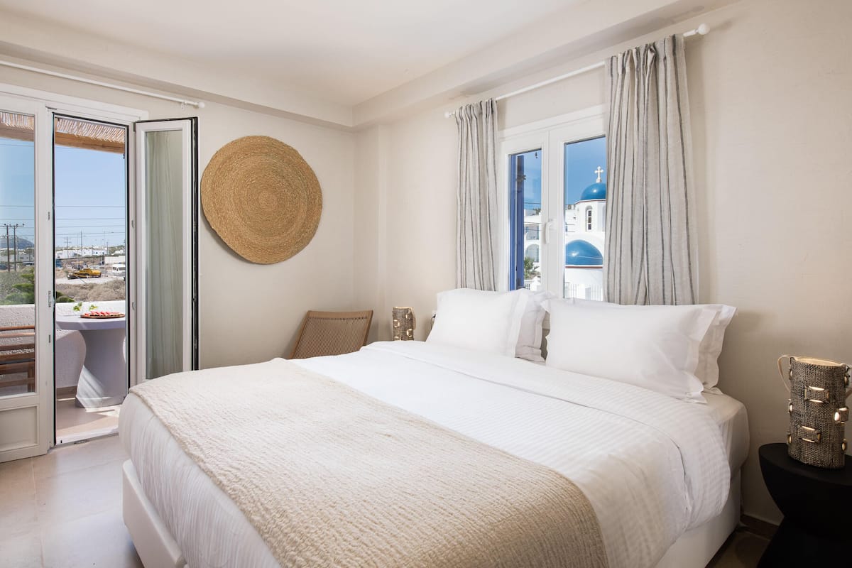 Quarto com uma cama grande, um painel redondo de tecido e vista para um edifício com cúpula azul pela janela.