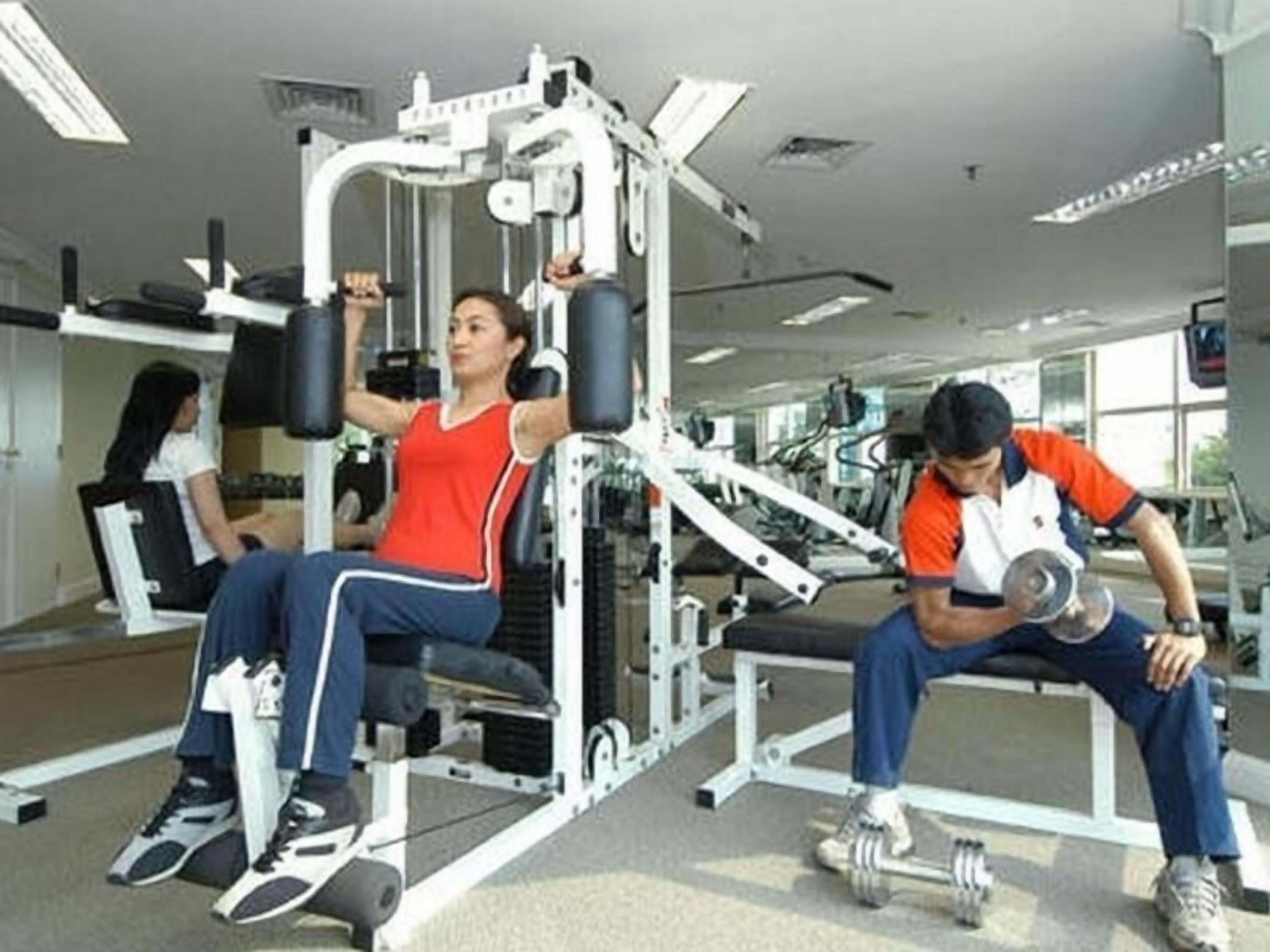 Un gimnasio con equipo de ejercicio, incluyendo una máquina de remo sentado y una prensa de banca.