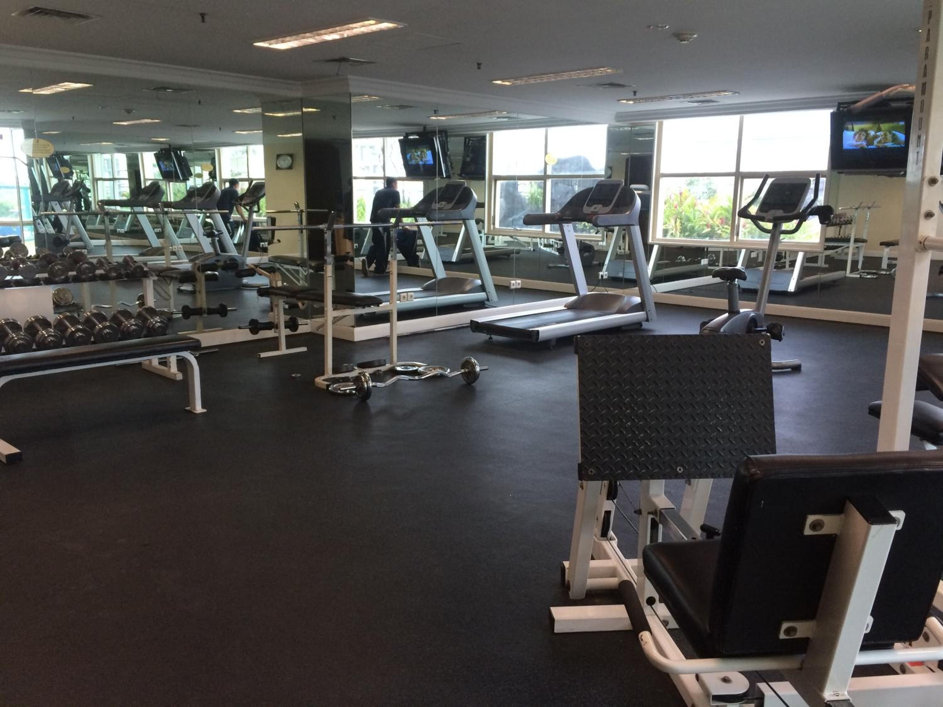 Een fitnessruimte met loopbanden, krachtapparaten en gewichten.