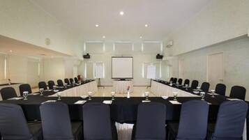 A conference room with a long table, chairs, and a projector screen.