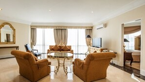 A spacious living room with a large mirror, two sofas, a coffee table, and a television. - Batavia Hotel and Serviced Apartments (Jakarta)