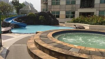 Una piscina con tobogán, un jacuzzi y una formación rocosa.