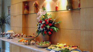 A buffet setup with various food items and a large floral centerpiece. - Batavia Hotel and Serviced Apartments (Jakarta)