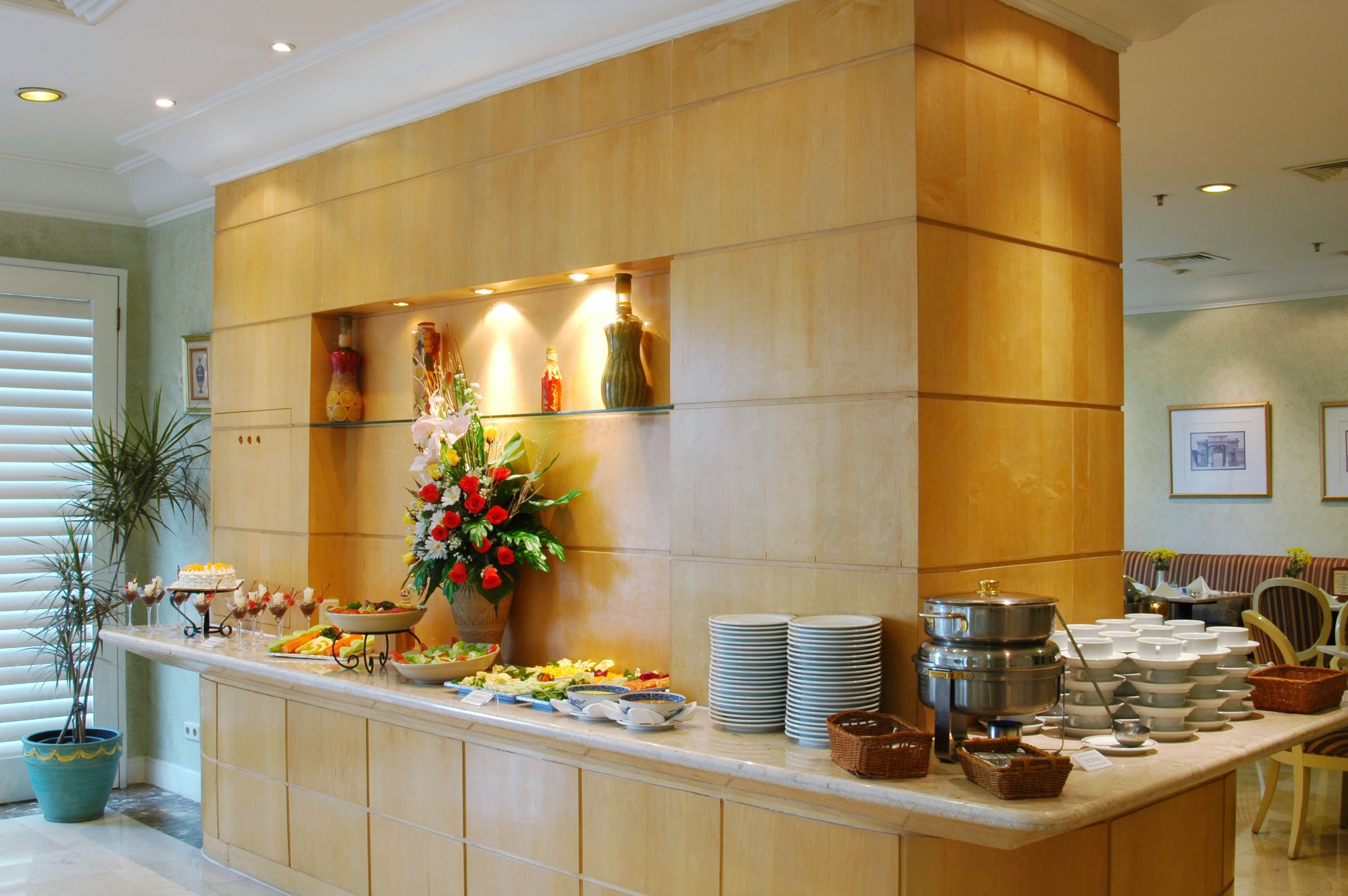 A buffet setup with various dishes, a vase of flowers, and a coffee station.