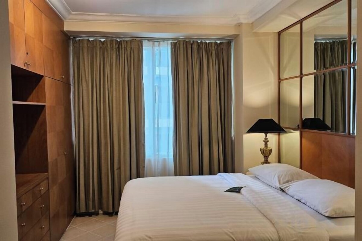 Une chambre d’hôtel avec un lit, une table de chevet, une lampe et une armoire.