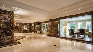 A spacious lobby with a marble floor, a large potted plant, and a seating area with chairs and a table. - Batavia Hotel and Serviced Apartments (Jakarta)