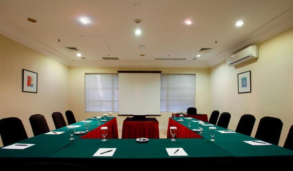 A conference room with a long table, chairs, and a projector screen.