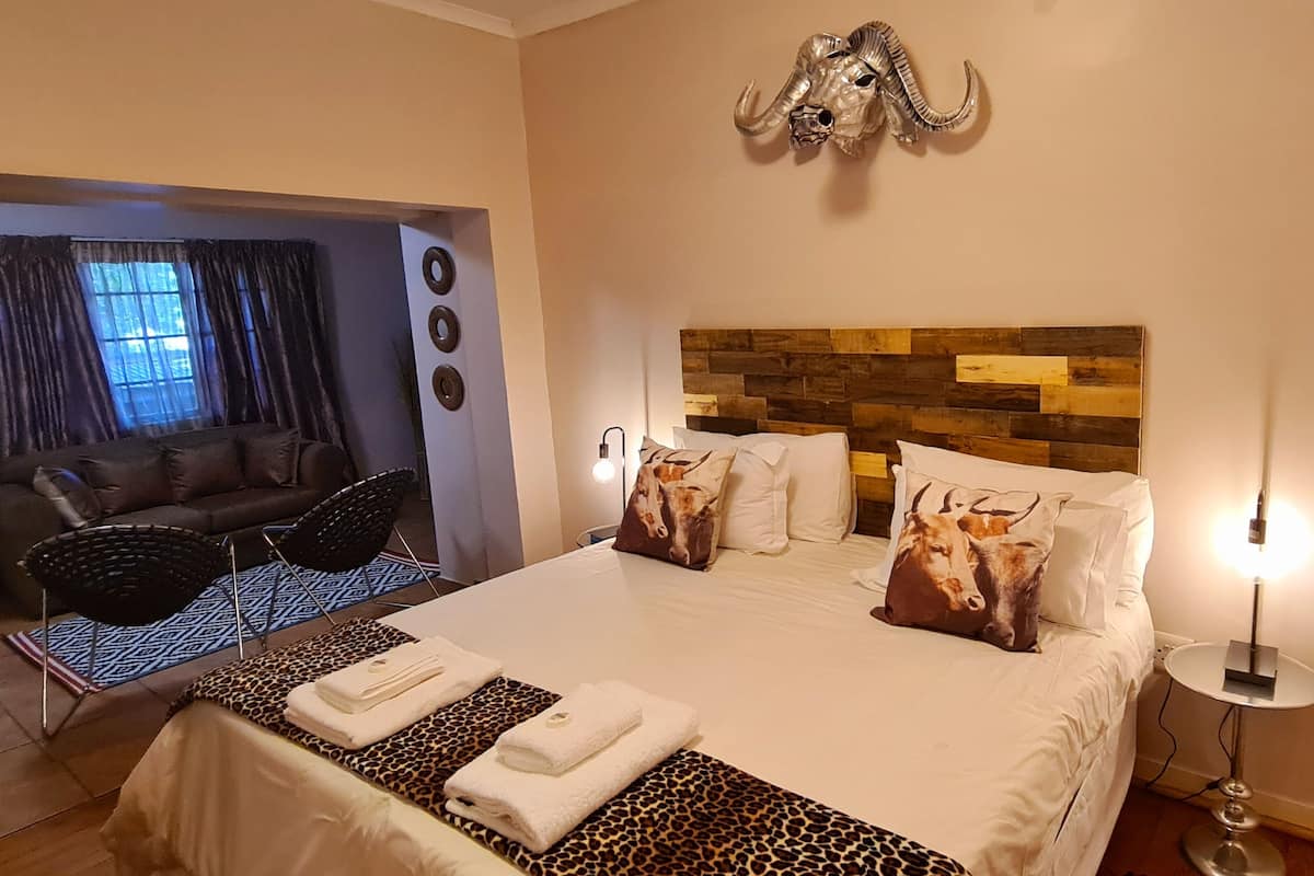 Habitación de hotel con cama, sofá, zona de comedor y vistas al exterior.