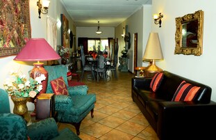 A living room with a dining area, featuring a sofa, chairs, a table, and lamps.