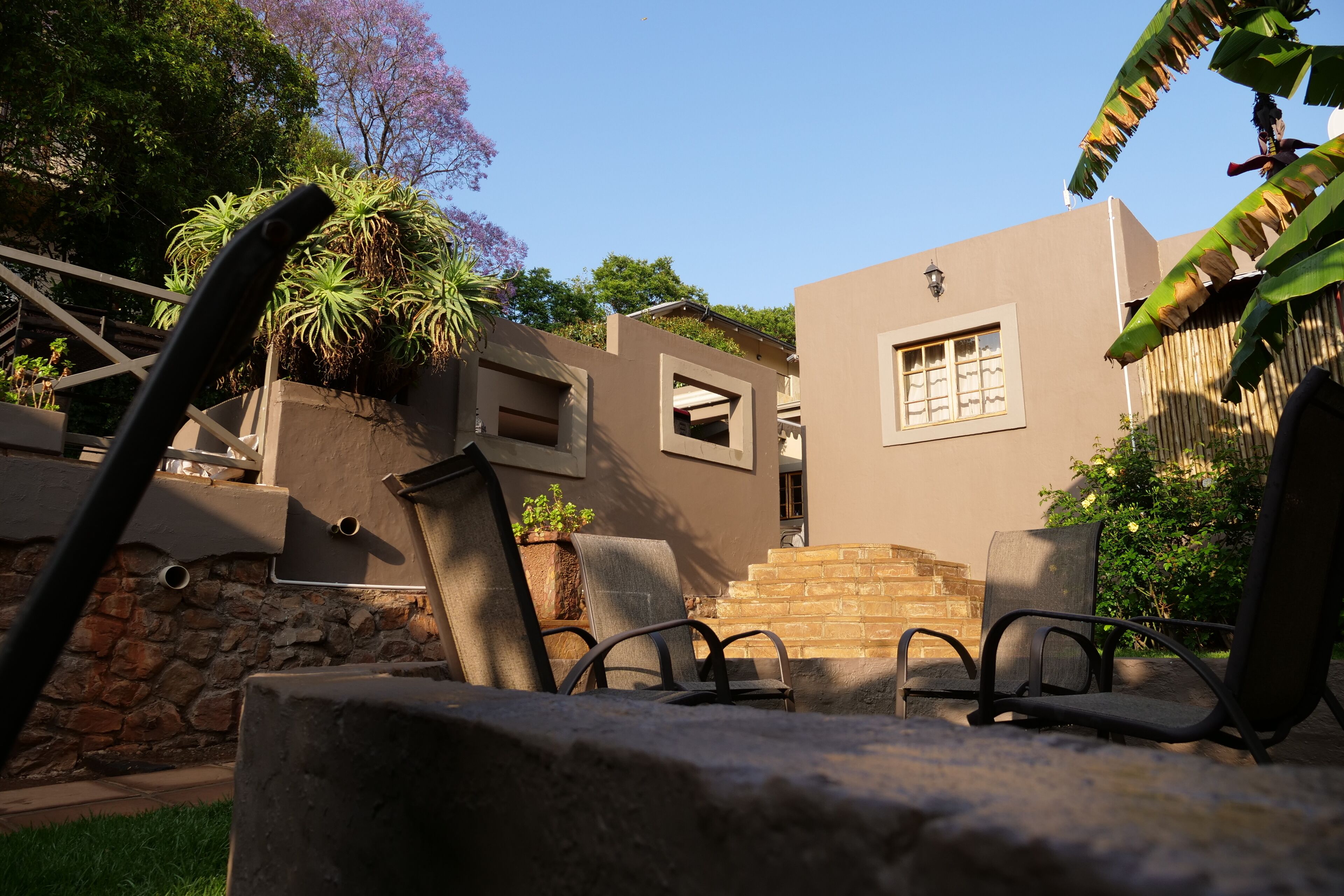 A patio area with outdoor seating, a stone wall, and a building with a window and a door.
