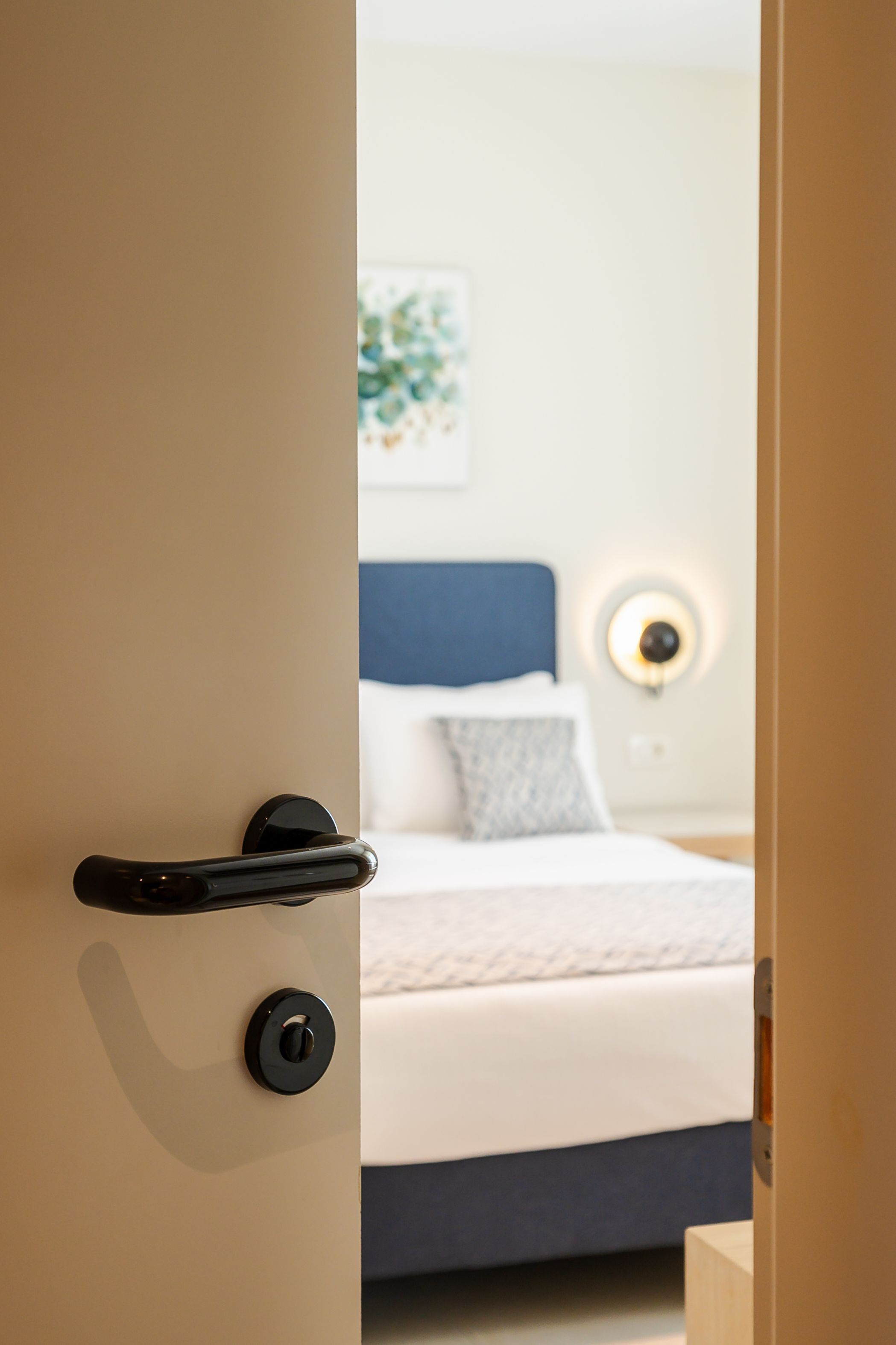 Een slaapkamer met een bed, een nachtkastje en een wandlamp.