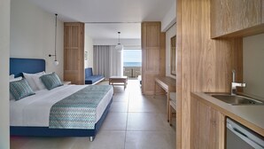 Habitación de hotel con cama, escritorio, lavamanos y vistas al mar.