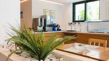 A modern kitchen with a central island, a coffee machine, and a window with a view of greenery.