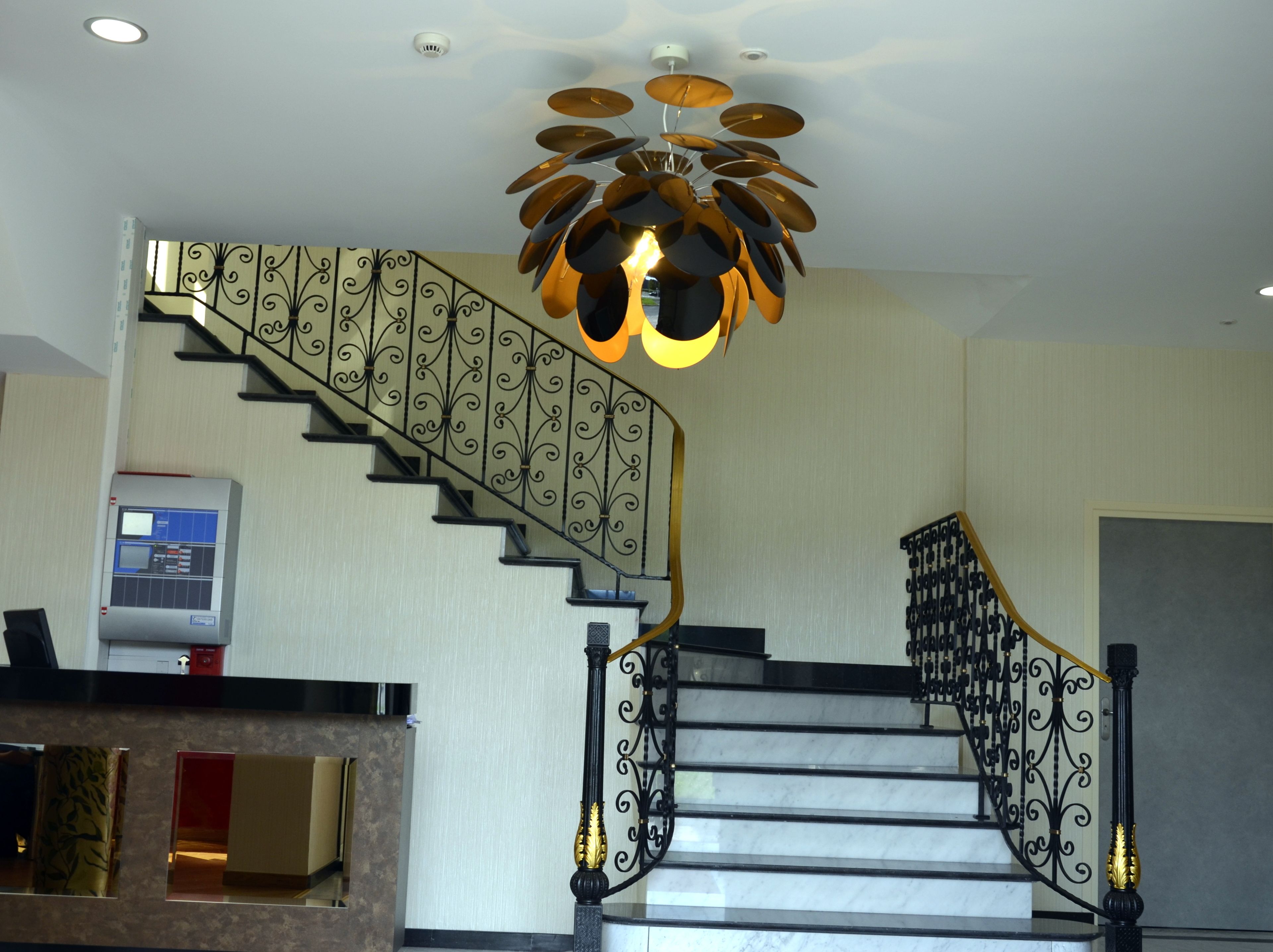 Un escalier orné de rampes noires et d’un lustre moderne.