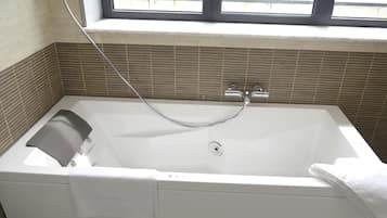 A modern bathroom with a bathtub, a window above it, and a towel rack.