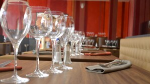 Mesa de jantar com vários copos de vinho e talheres, indicando um ambiente de restaurante.