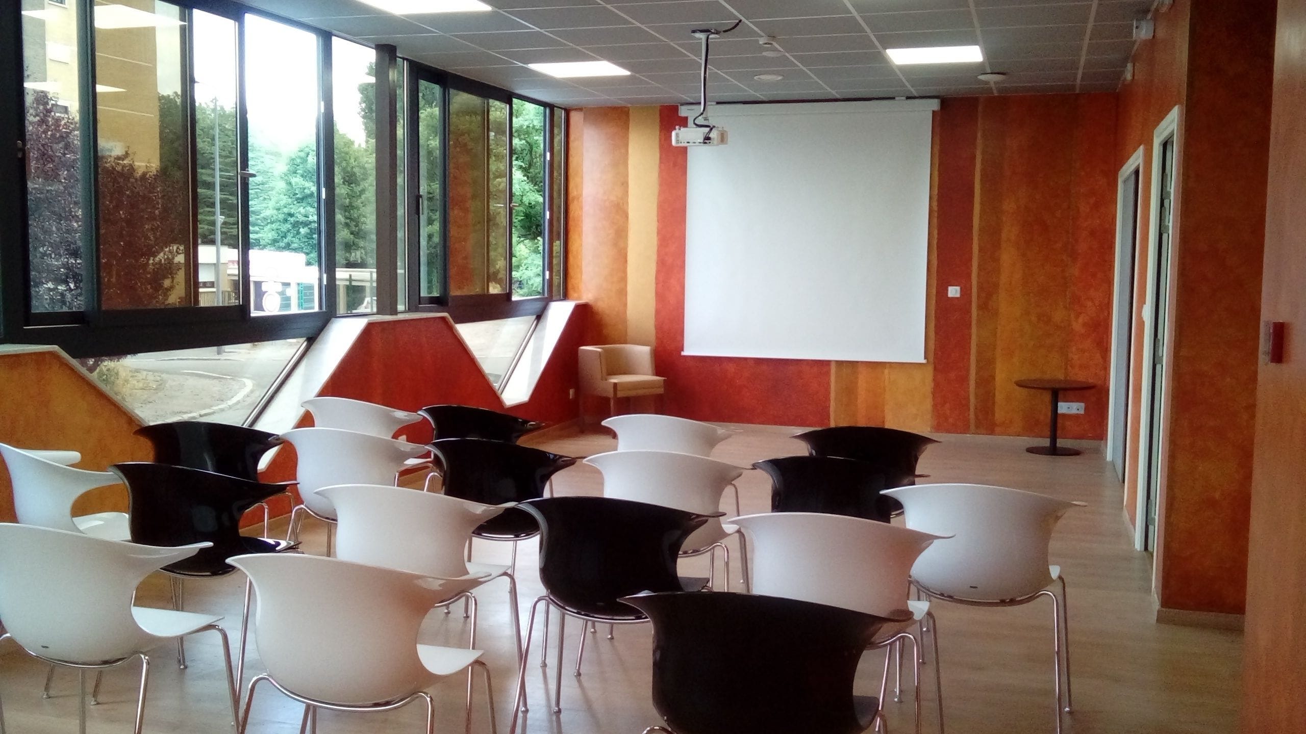 A conference room with rows of chairs, a projector screen, and large windows.