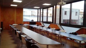 Ett konferensrum med ett långt bord, stolar och en projektor.