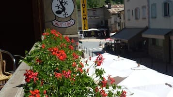 Eine Terrasse mit roten Blumen und Sitzgelegenheiten im Freien.