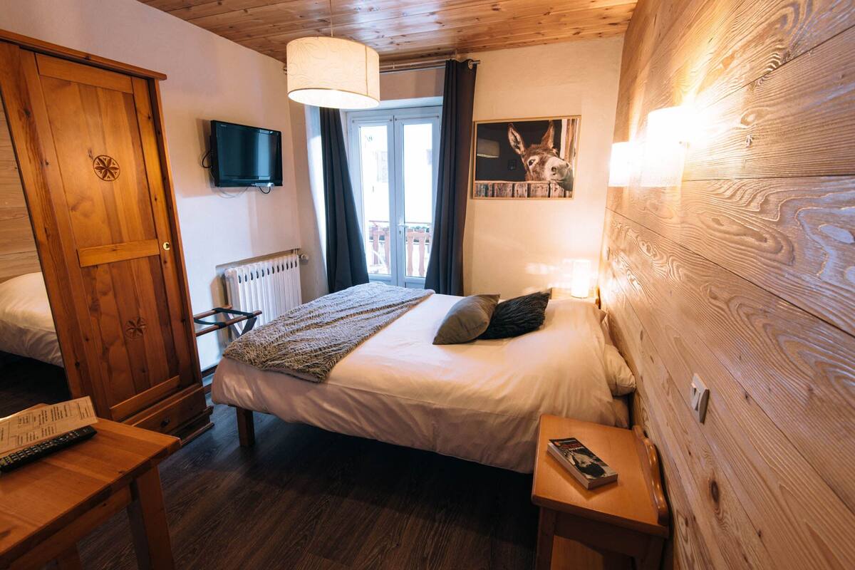 A bedroom with a bed, bedside table, and a TV.