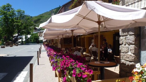 A row of outdoor tables with white umbrellas, surrounded by vibrant flowers. - Hôtel Châlet de Lanza (Abriès-Ristolas)