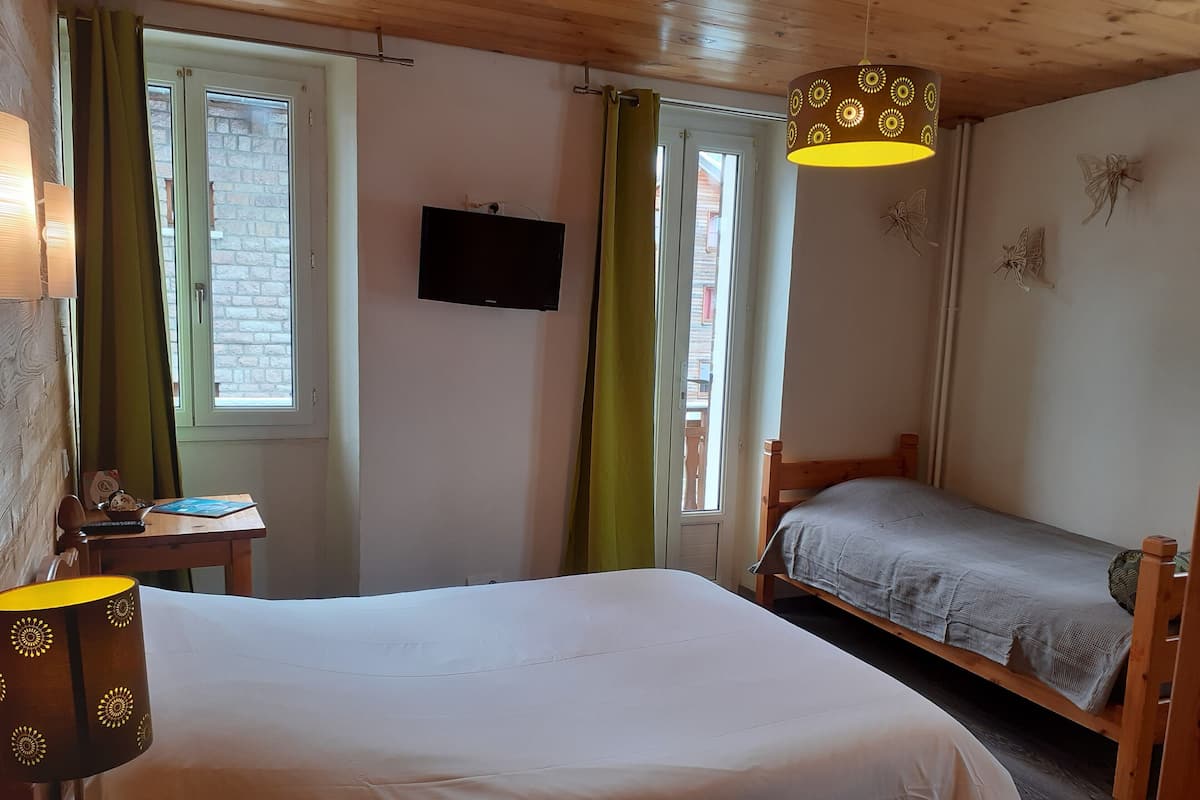 A bedroom with a bed, a TV, and a desk.