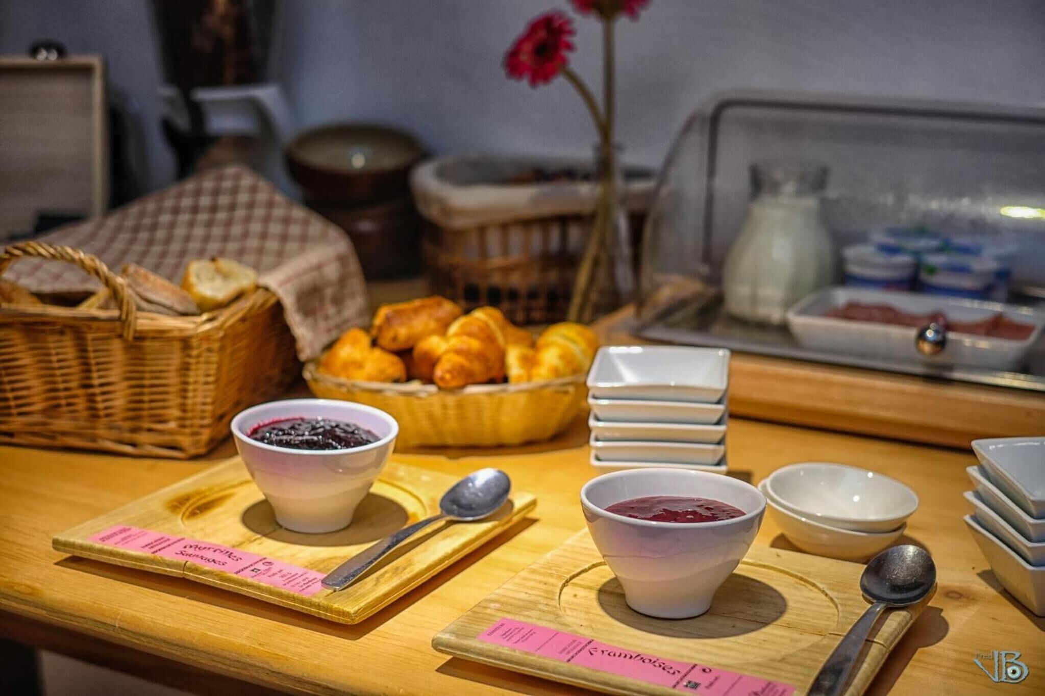A breakfast buffet with various pastries, bowls of jam, and a milk jug.