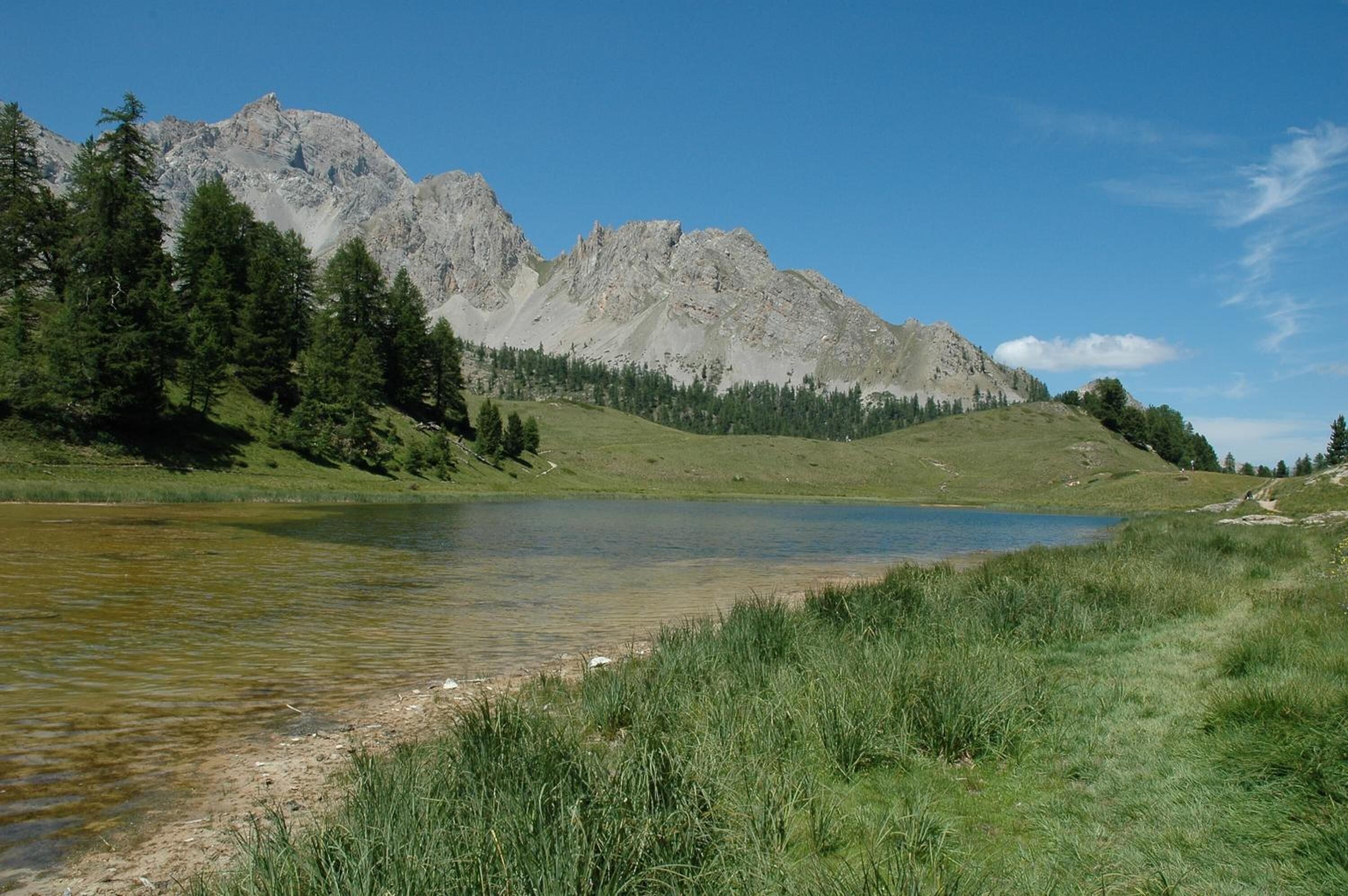 A mountain landscape with a lake and forested hills.