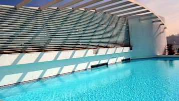 A swimming pool with a curved roof structure and a tiled edge.