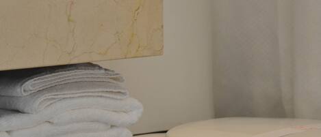 A bathroom with a marble vanity, a stack of white towels, and a toilet.