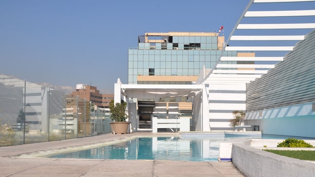 A modern building with a pool area, including a clear pool, potted plants, and a seating area. - Rentasuite (Santiago)