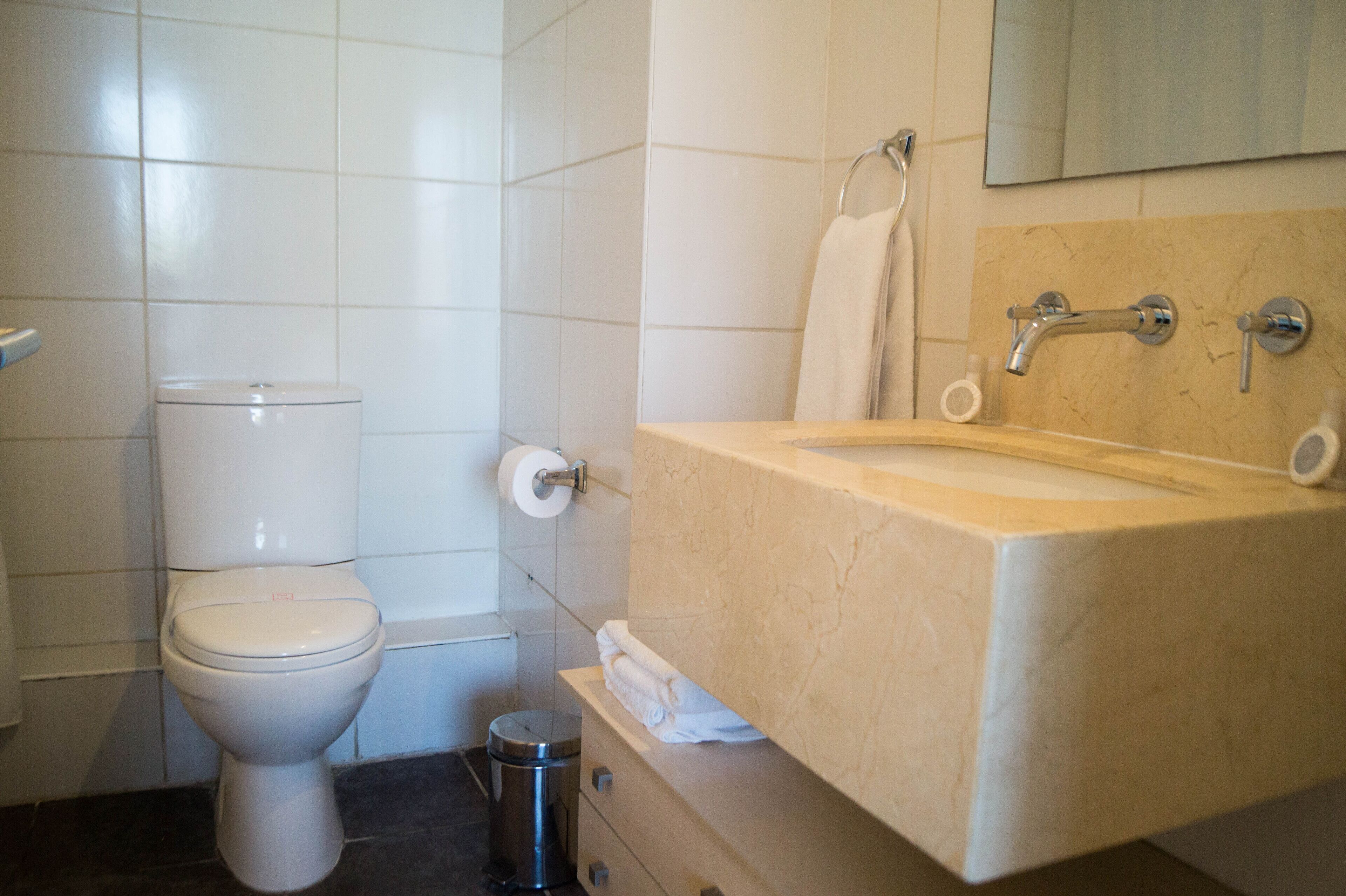 A bathroom with a toilet, sink, and mirror.
