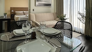 A modern hotel room with a dining area, a sofa, and a bed. - Rentasuite (Santiago)
