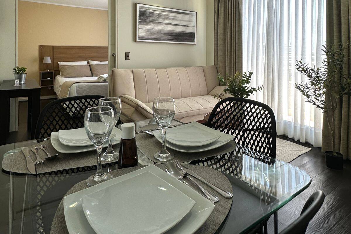 A modern hotel room with a dining area, a sofa, and a bed.