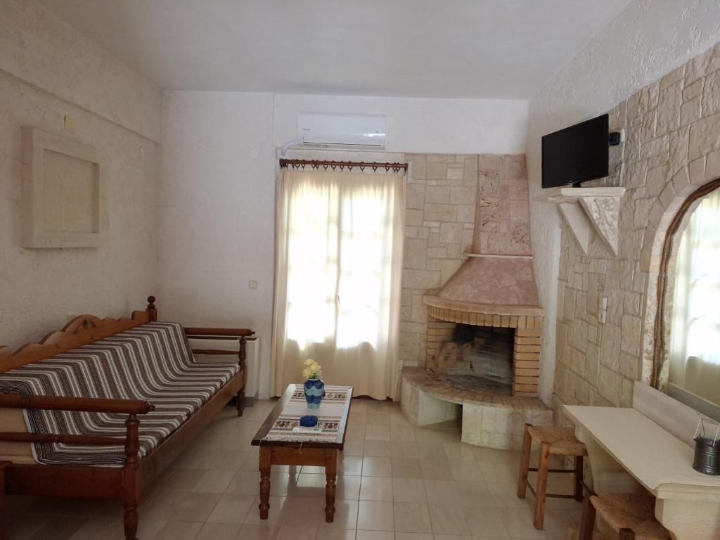 Una sala de estar con un sofá, una mesa con un florero, una chimenea y un televisor montado en la pared.
