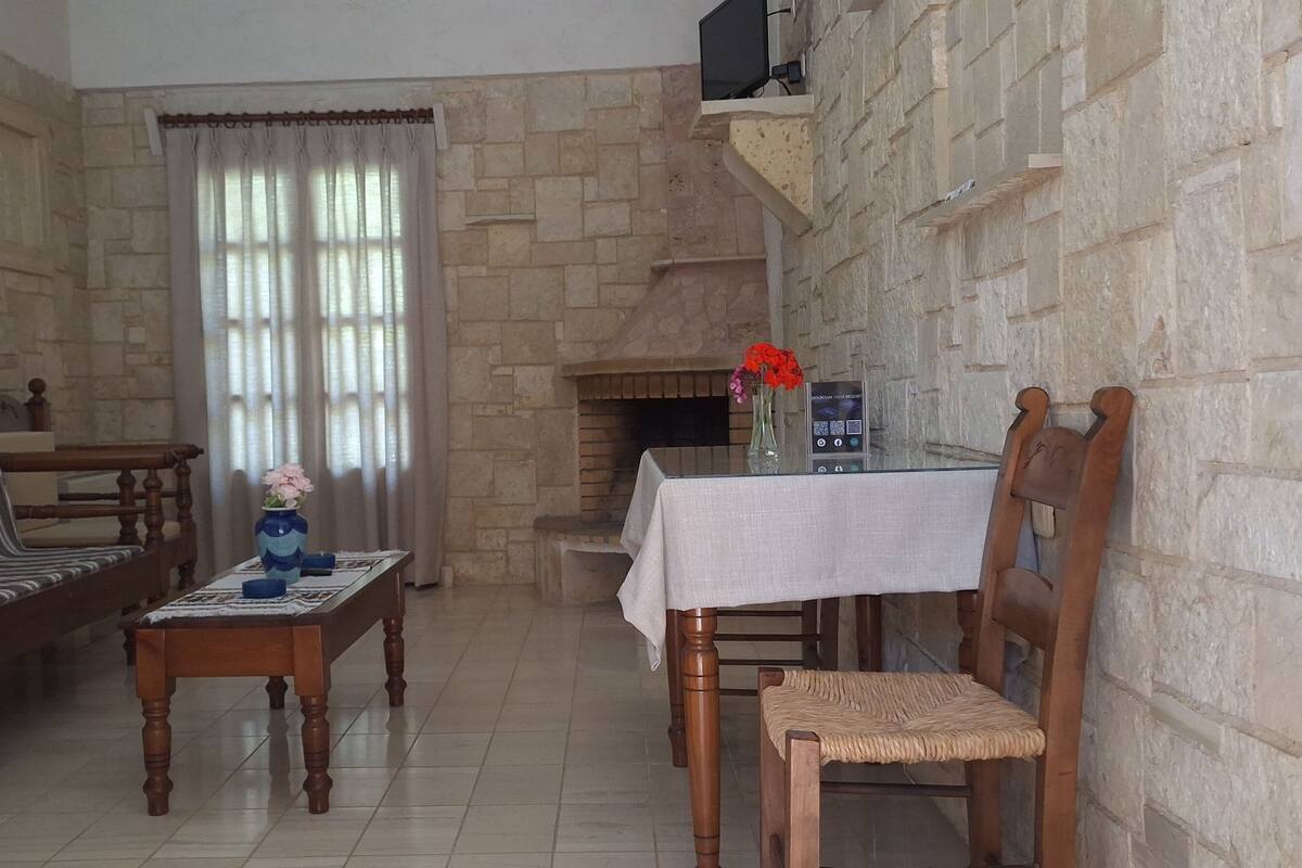 Una sala de estar con sofá, una mesa de madera, una silla, chimenea y pared de piedra.