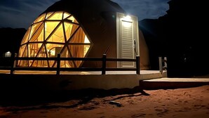 A dome-shaped building with a door and windows, surrounded by a fence and set against a night sky with stars. - Beyond Wadi Rum Camp (Wadi Rum)
