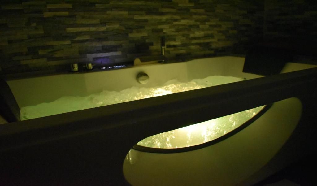 A spa area with a bathtub filled with water, a stone wall, and a modern light fixture.