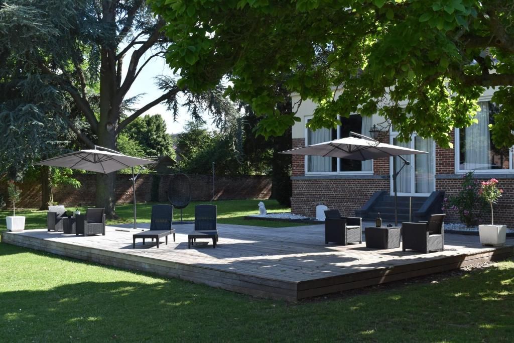 An outdoor patio with seating and umbrellas, surrounded by a brick building and greenery.