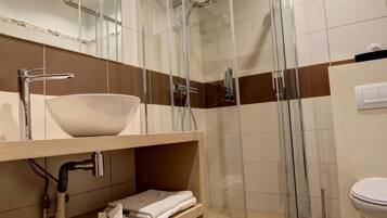 A modern bathroom with a glass-enclosed shower, a sink with a vessel basin, and a toilet.