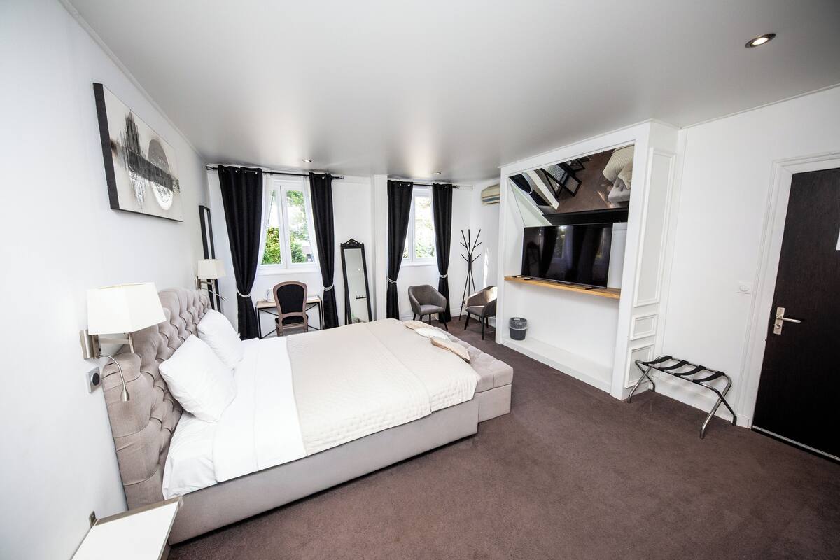A modern hotel room with a large bed, a desk, and a chair.